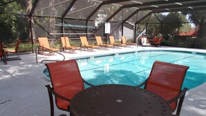 A covered outdoor pool area with lounge chairs and a table.