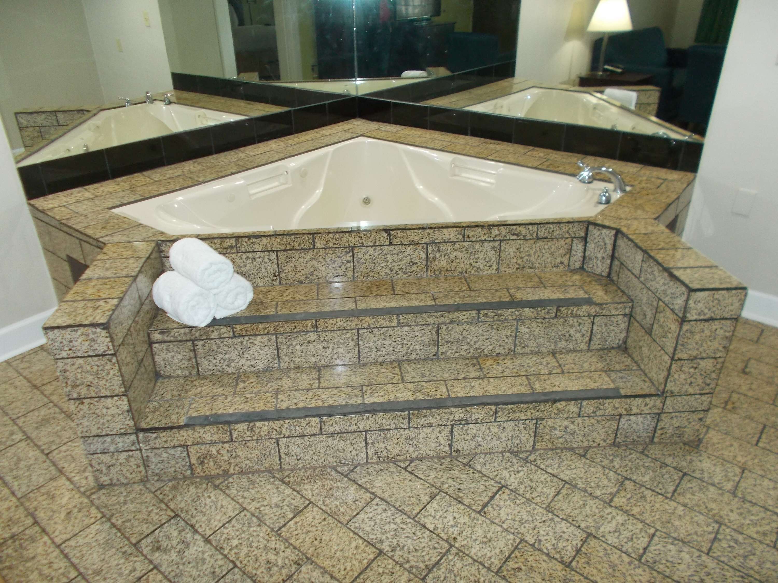 A bathroom with a large bathtub, a separate sink, and a mirror above the sink.
