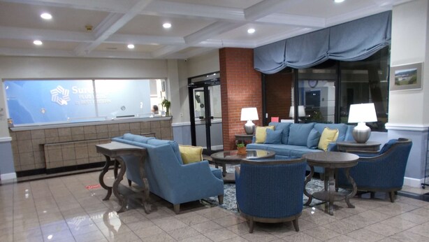 A lobby with a reception desk, blue sofas, and a tiled floor.
