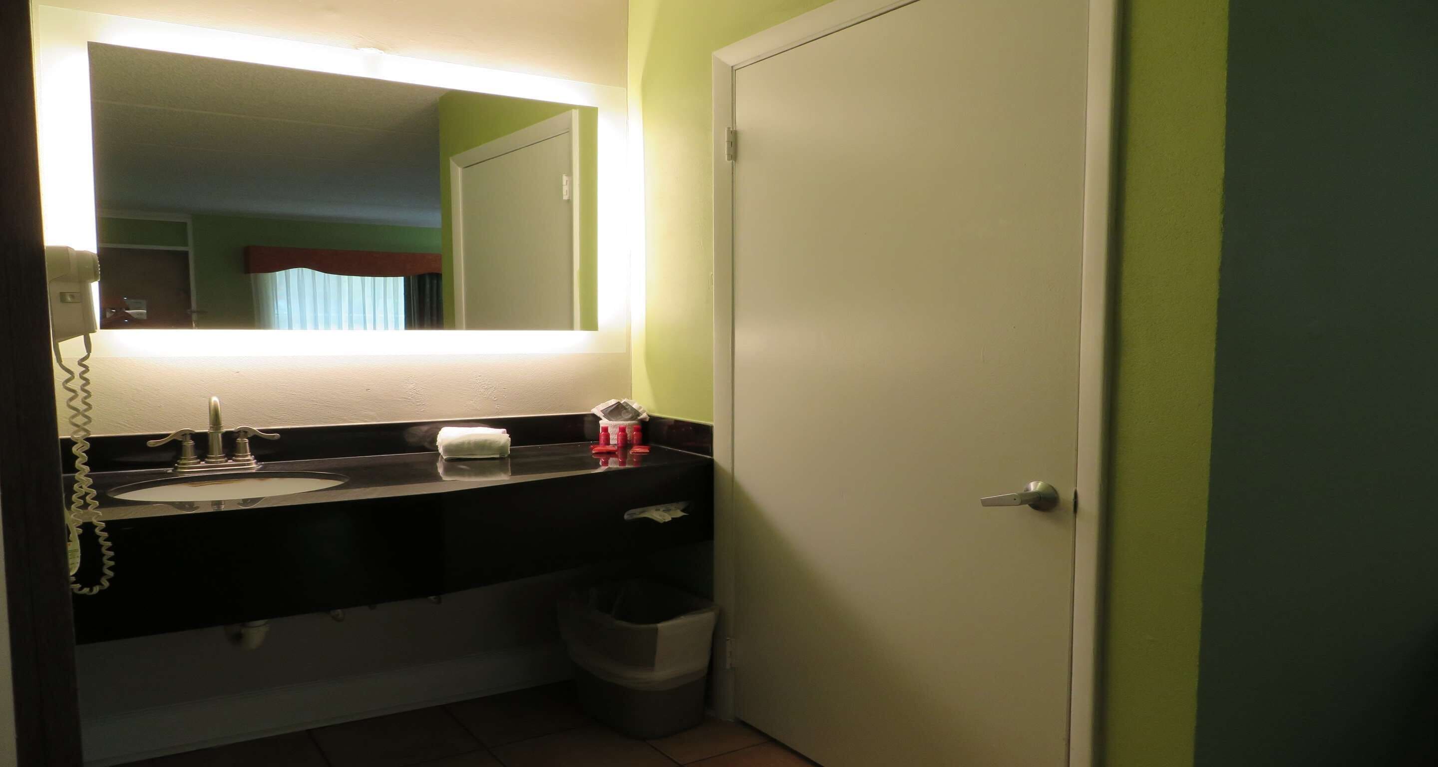 Un baño con un lavabo negro, un espejo y una puerta blanca.