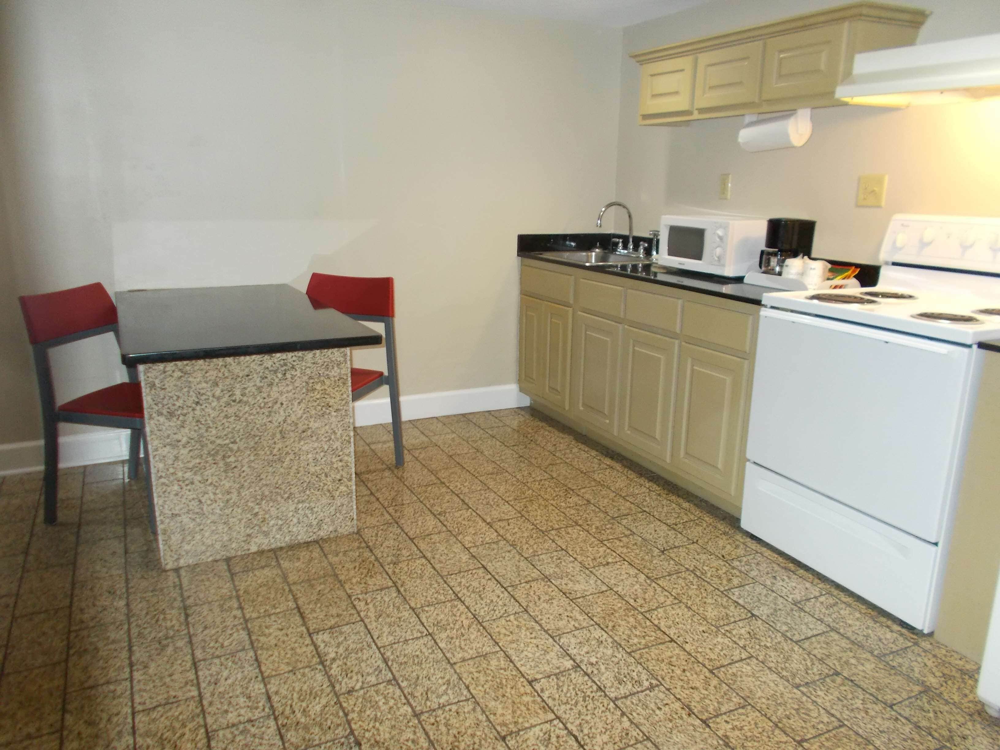 Una pequeña cocina con una mesa y sillas, un microondas, una estufa y armarios.
