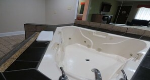 A modern bathroom with a large bathtub, a separate shower area, and a vanity with a mirror.
