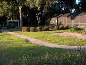 A well-maintained garden with a paved walkway, neatly trimmed hedges, and a building with a modern design.