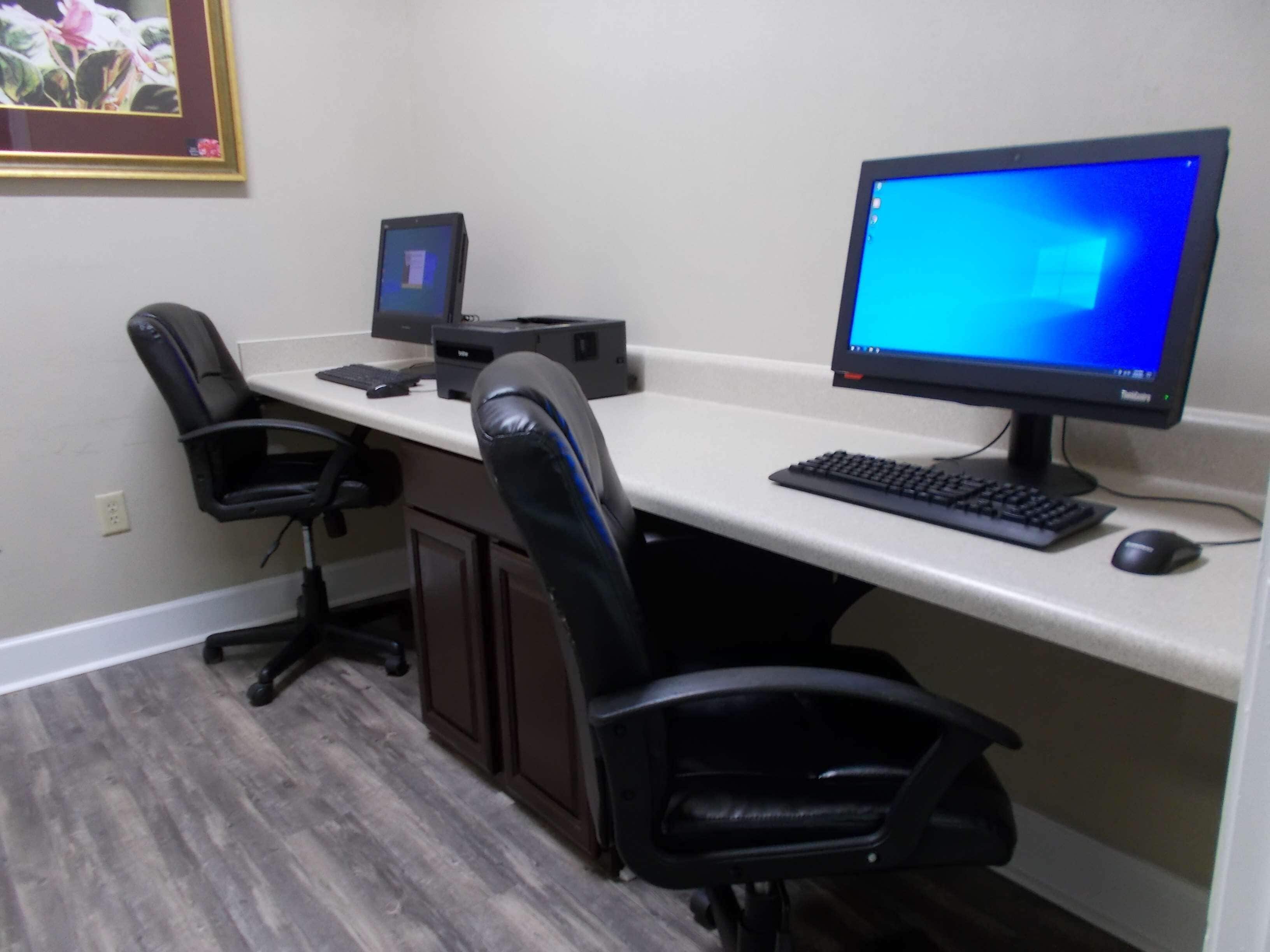 Un espacio de trabajo en casa con un escritorio, dos sillas de oficina negras, un ordenador de sobremesa, un monitor, un teclado y un ratón.