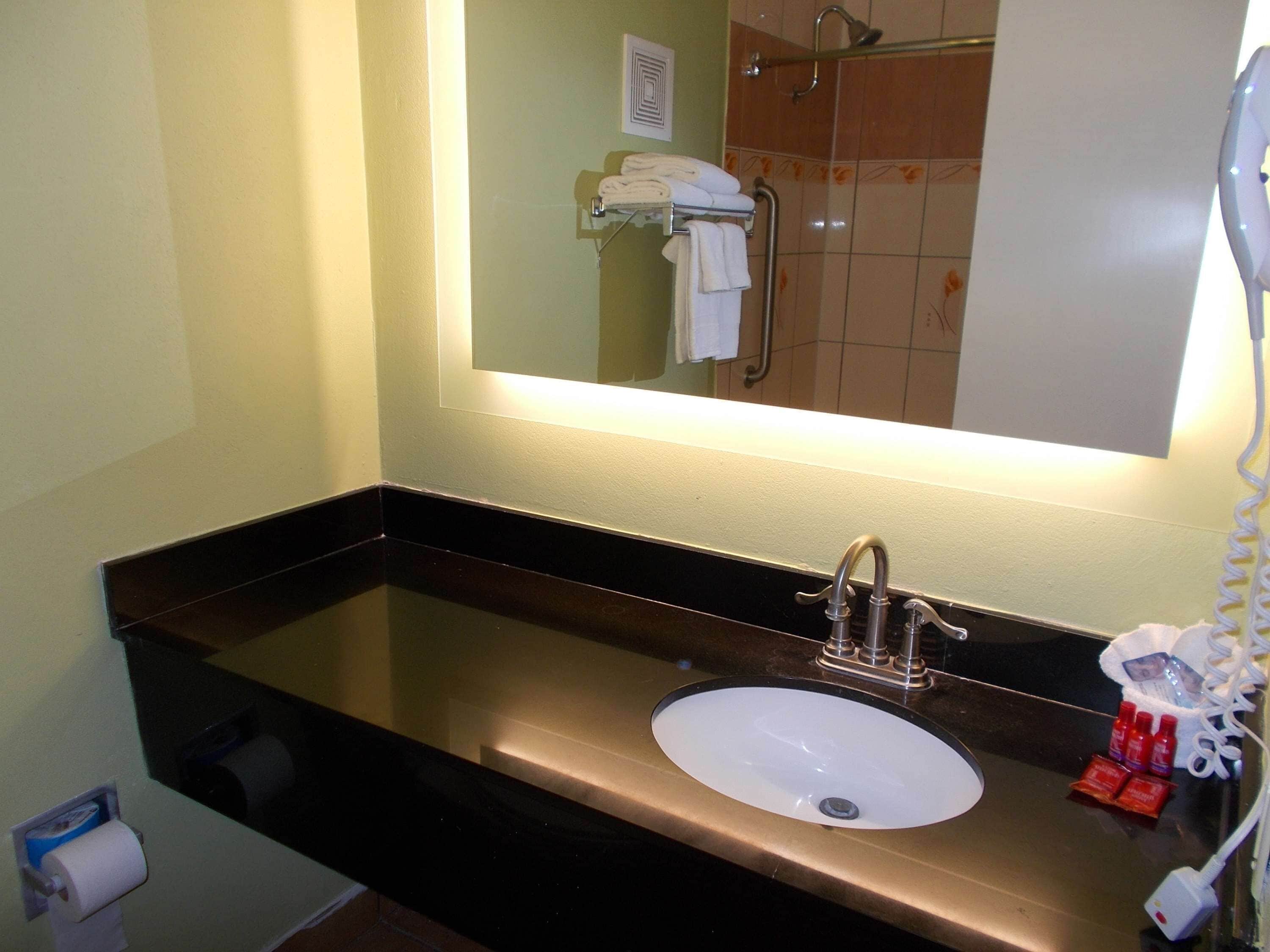 Un baño con lavabo, espejo y toallero.