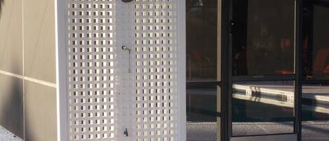 A white metal fence with a grid pattern, a metal door with a handle, and a glass window with reflections.