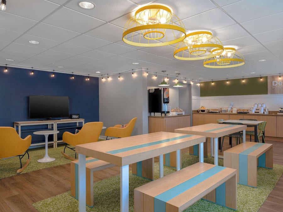 Un espace de détente moderne, doté de tables, de chaises et d’un téléviseur.