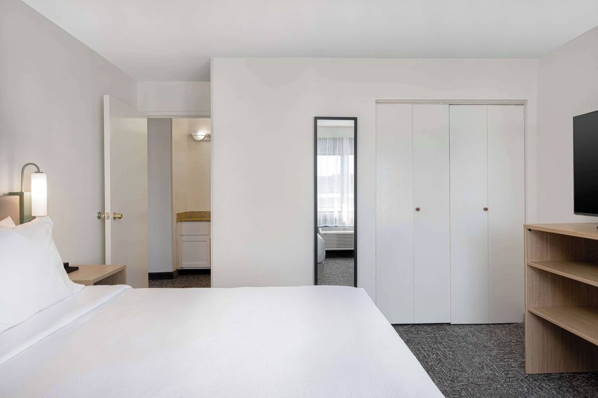 A hotel room with a bed, a TV, a desk, and a wardrobe.