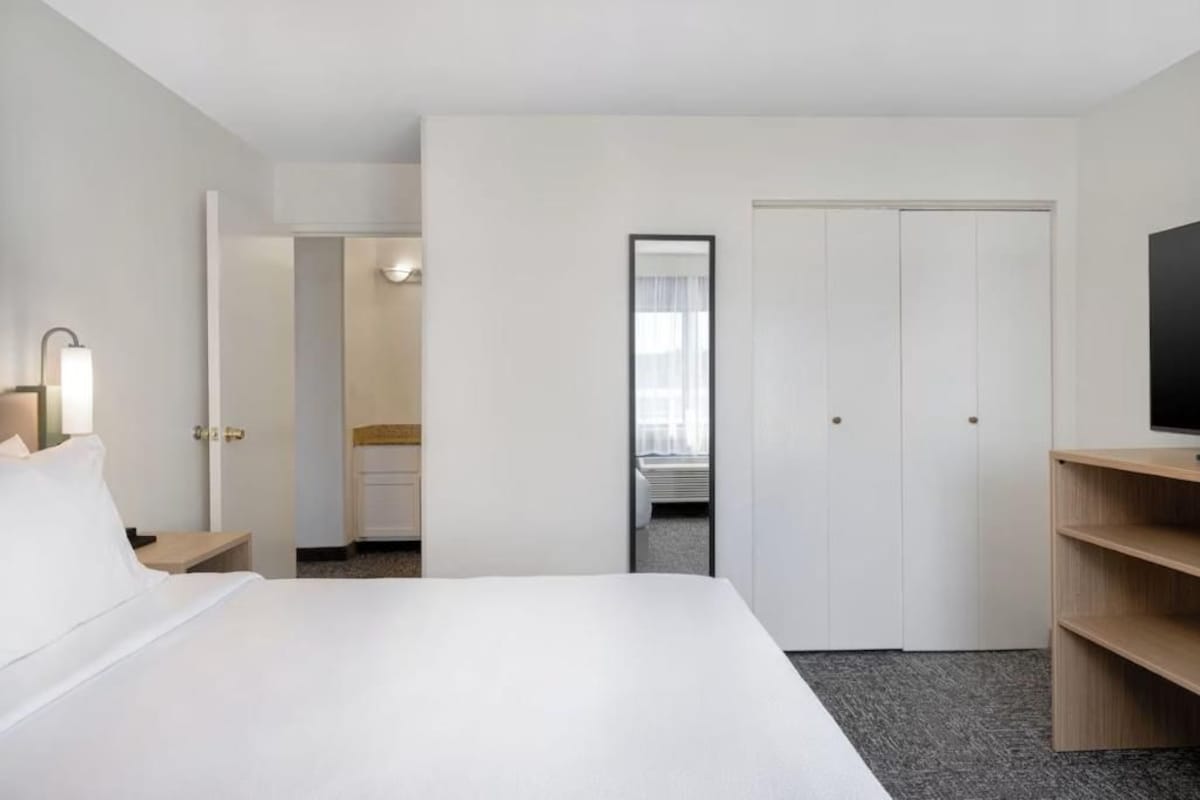 A hotel room with a bed, a television, a desk, and a wardrobe.