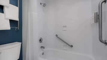 A bathroom with a bathtub, a toilet, a shower, and a handrail.
