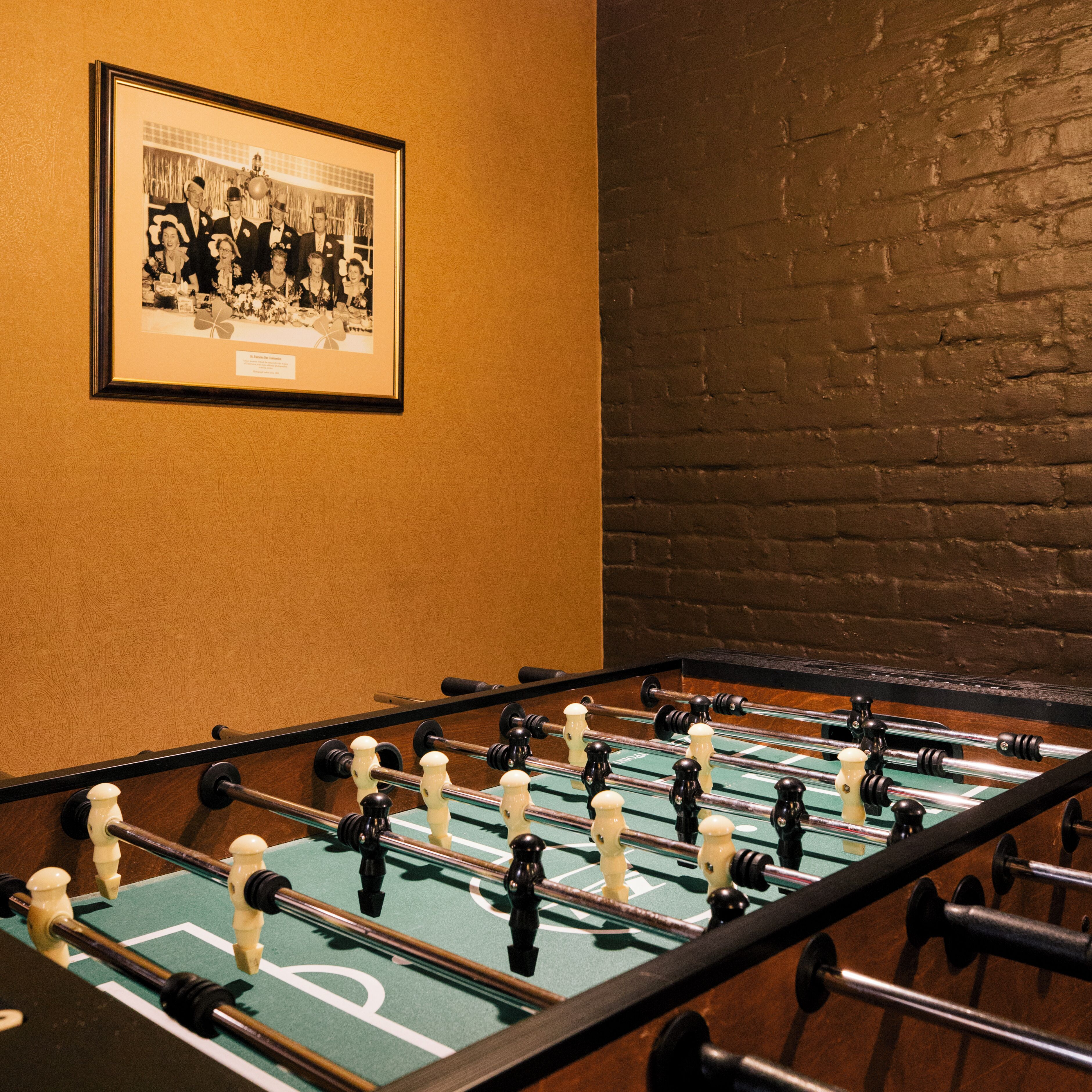 Una mesa de fútbol de mesa en una habitación con una fotografía blanco y negro enmarcada en la pared.