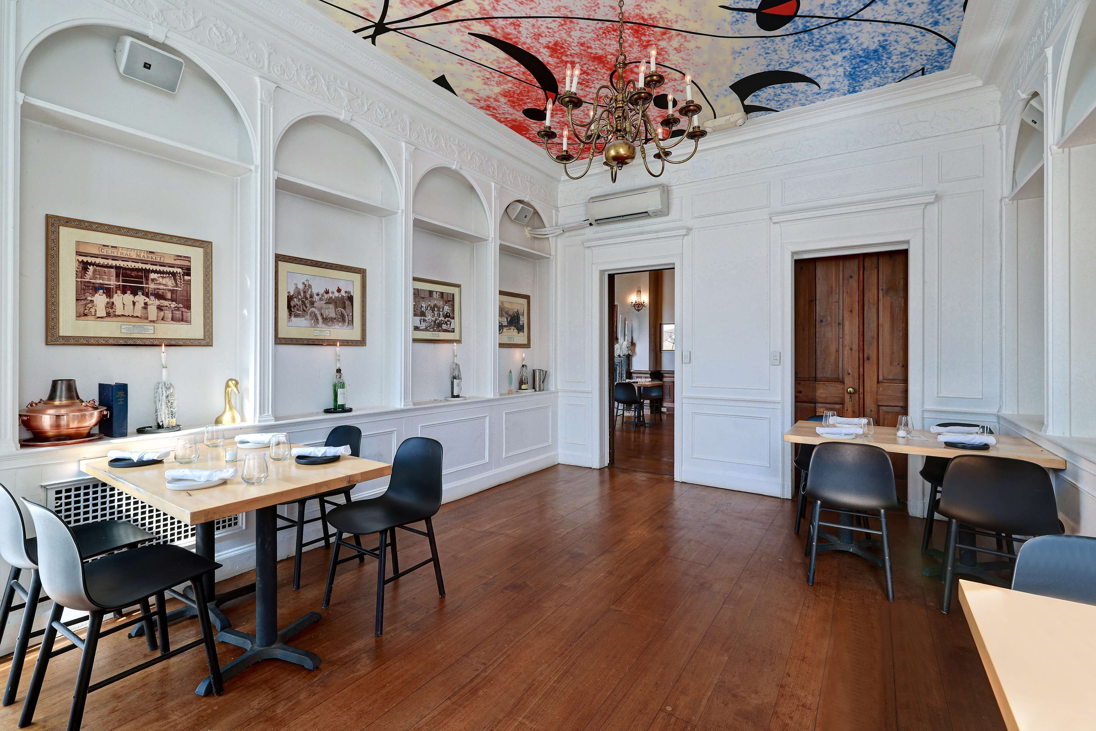 Un'area pranzo con tavolo e sedie in legno, quadri appesi al muro e un lampadario.