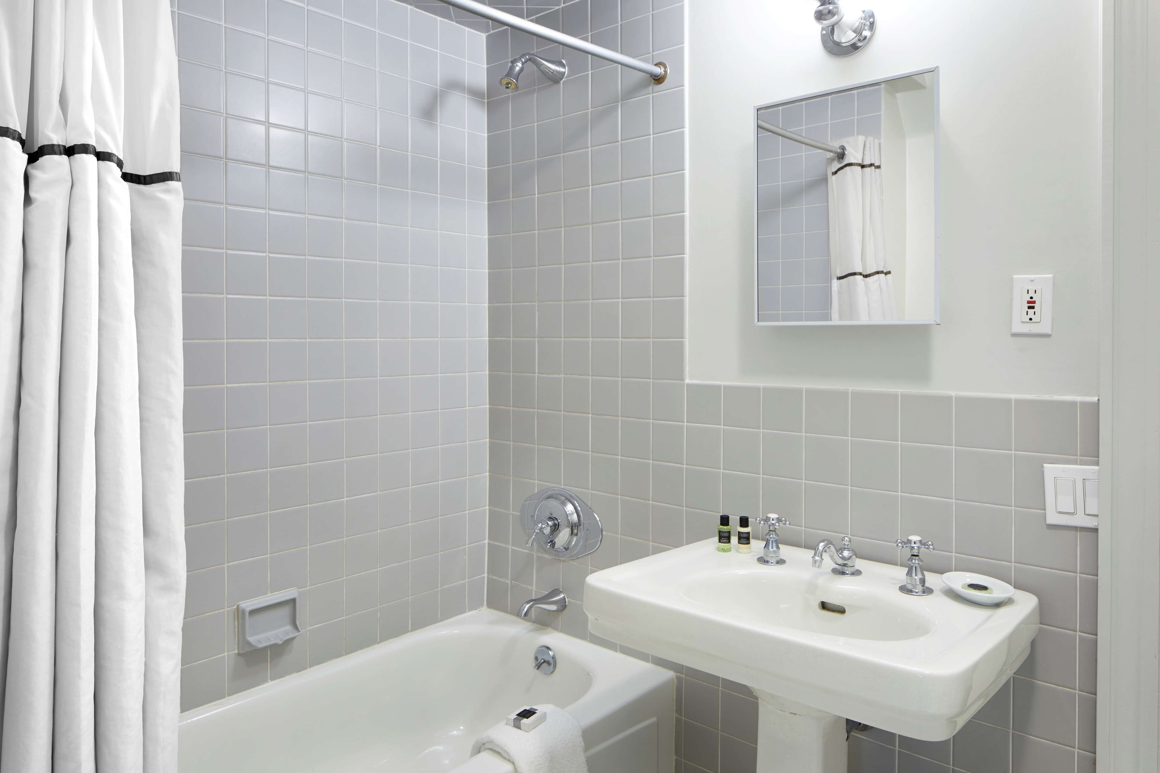 A bathroom with a bathtub, a sink, and a mirror.