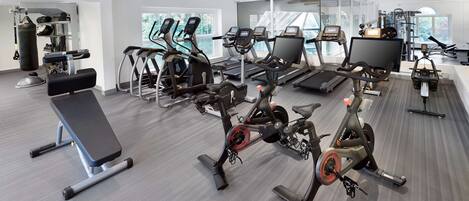 Un gimnasio moderno con cintas de correr, bicicletas estáticas y máquinas de pesas.