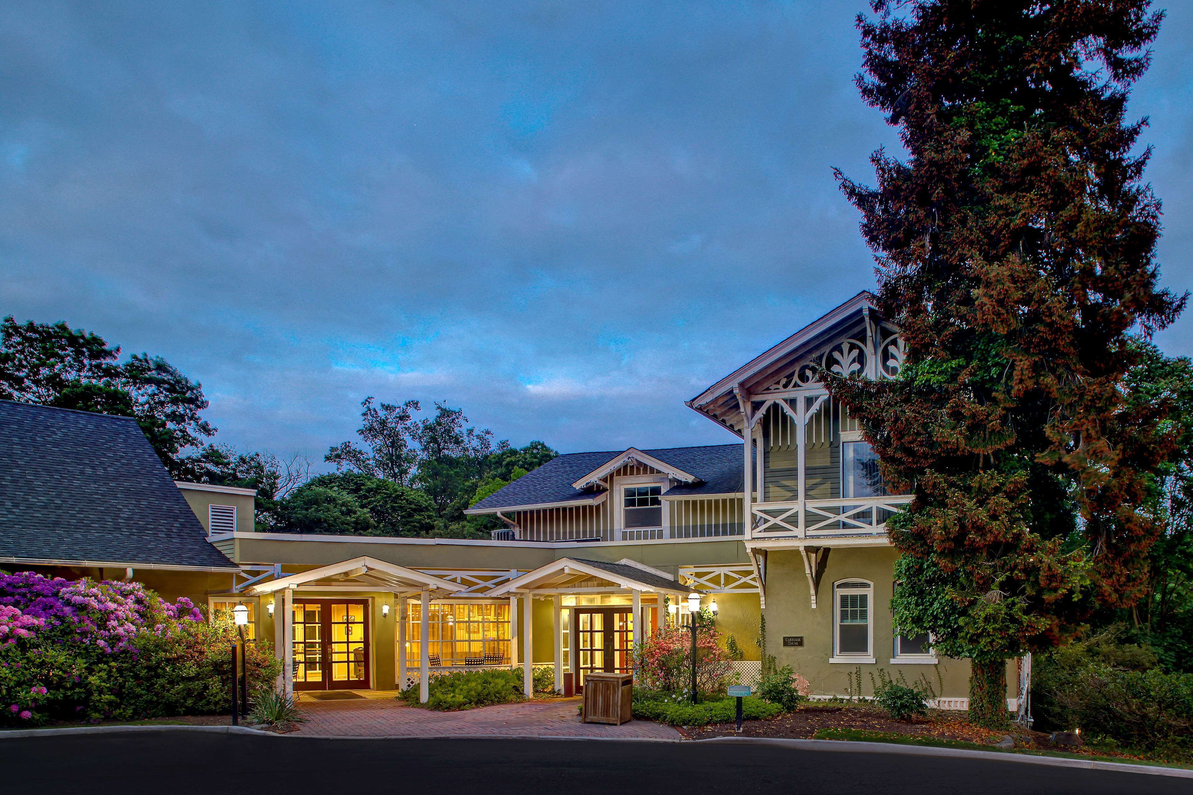 A two-story building with a porch and a large tree in front.