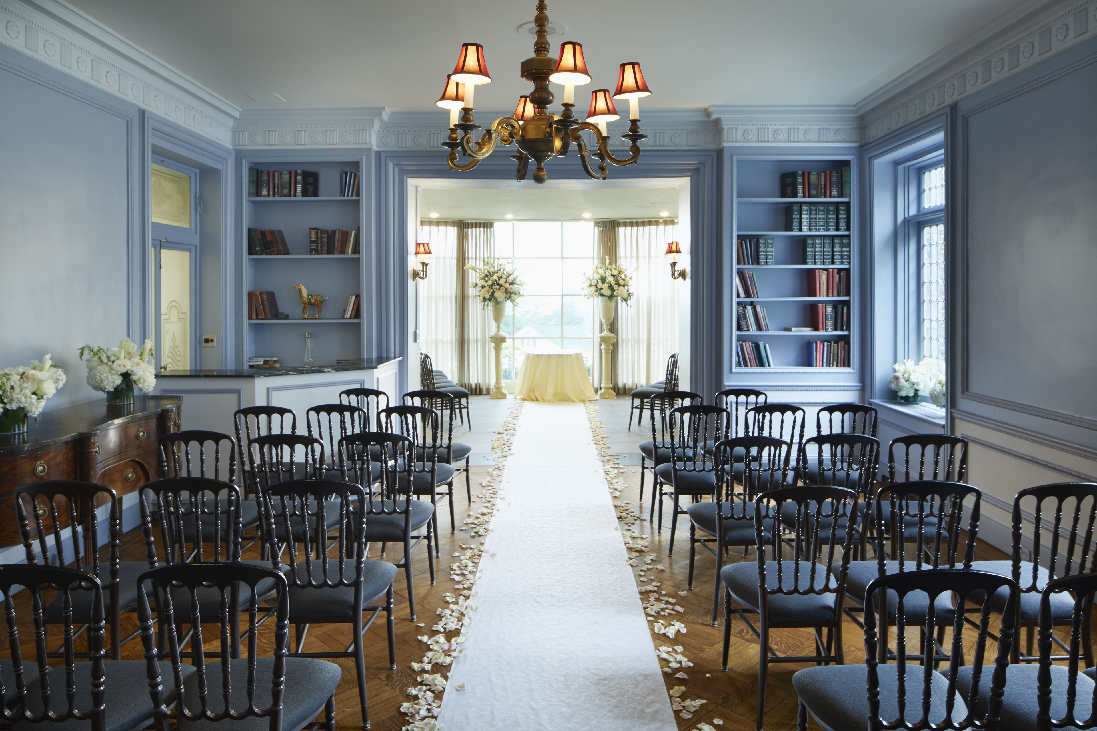 A formal room with rows of chairs, a white carpet, and bookshelves.
