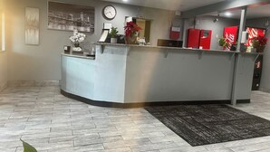 Un área de recepción con mostrador, reloj y refrigerador rojo.