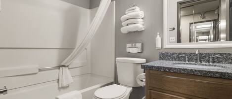 A bathroom with a bathtub, toilet, and vanity with a sink.
