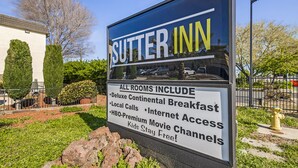 Señal de Sitter Inn destacando servicios como desayuno continental de lujo, llamadas locales, canales de cine HBO Premium y niños sin cargo.