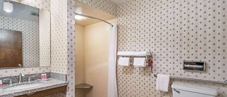 Un baño con lavamanos, espejo, ducha, inodoro y toallero.