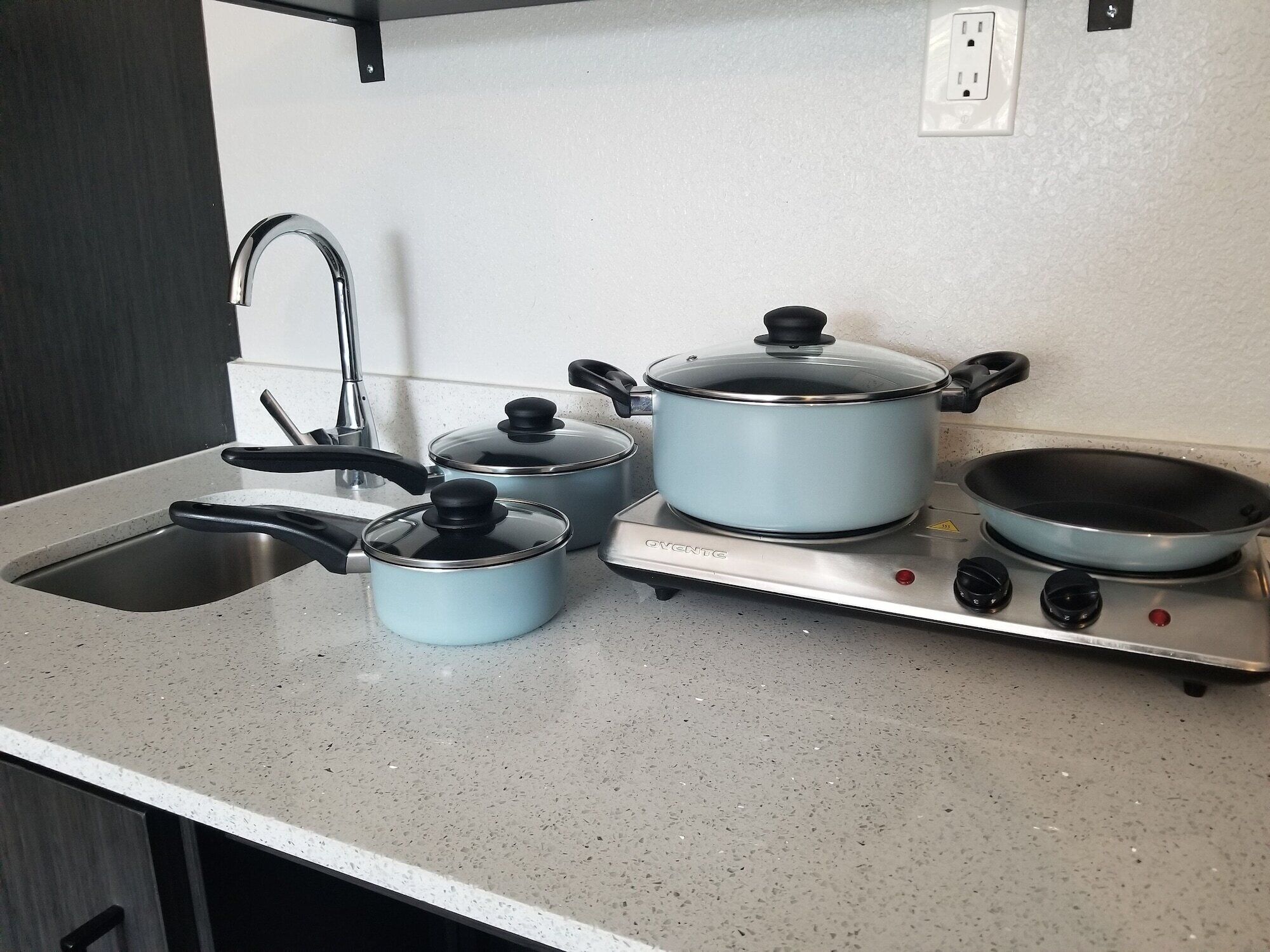 A kitchen with a sink, stove, and three pots.