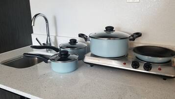 A kitchen with a sink, stove, and three pots.