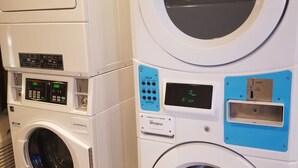 A stack of white commercial laundry machines with control panels and a coin return slot. - Studio 6 Sacramento, CA - Natomas & SMF Airport (Sacramento)