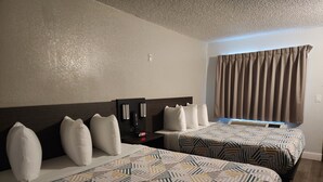 A hotel room with two beds, a nightstand with a coffee maker, and a window with curtains. - Studio 6 Sacramento, CA - Natomas & SMF Airport (Sacramento)