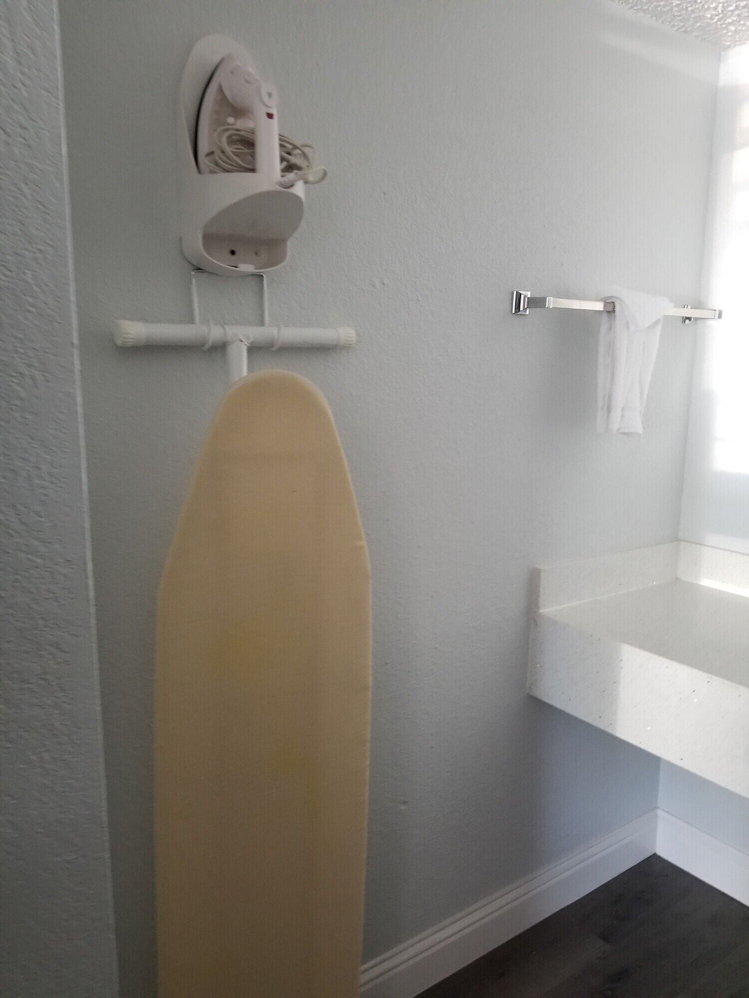 A bathroom with a white sink, a towel rack, and an ironing board.