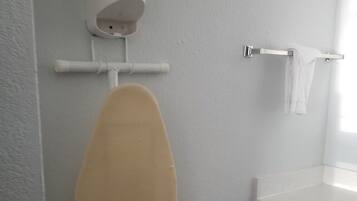 A bathroom with a white sink, a towel rack, and an ironing board.