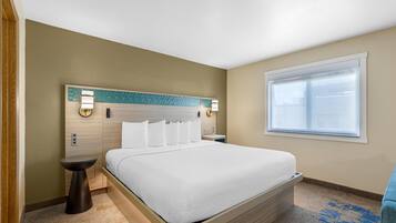 Une chambre d’hôtel avec un lit, des tables de chevet, une fenêtre et une tête de lit agrémentée d’appliques murales.