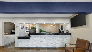 A reception area with a counter, a brown leather chair, and a TV mounted on the wall.