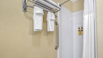 A bathroom with a shower curtain, a towel rack with towels, and two bottles of shampoo.