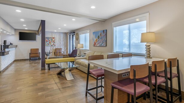 A modern kitchen with a dining area, wooden flooring, and a large window.