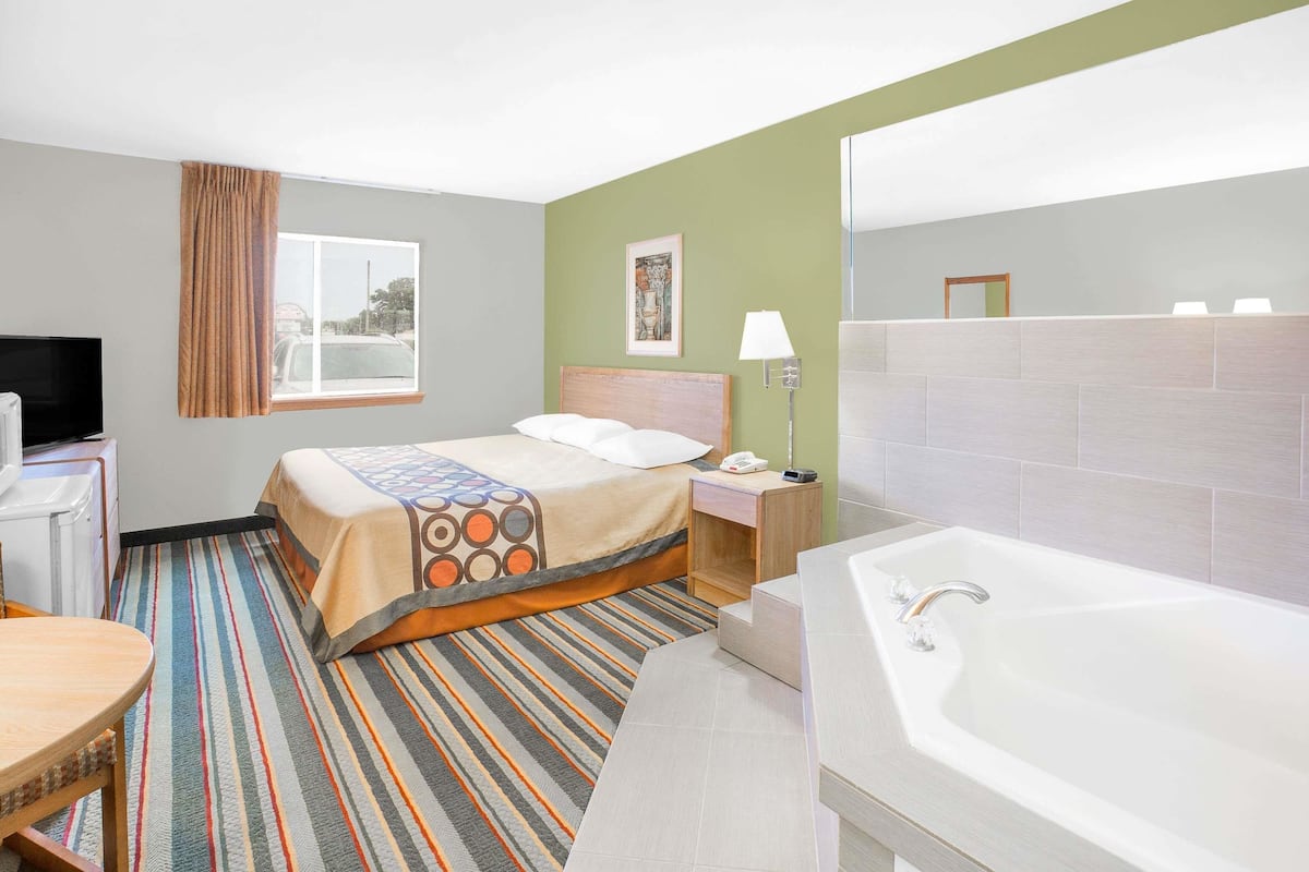 Une chambre d’hôtel comprenant un lit, une salle de bain avec baignoire, un bureau et un téléviseur.