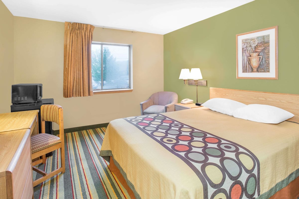 Une chambre d’hôtel équipée d’un lit, d’un bureau, d’une chaise, d’une télévision et d’une fenêtre avec des rideaux.