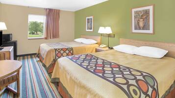 A hotel room with two beds, a desk, a chair, and a window with a view of trees.