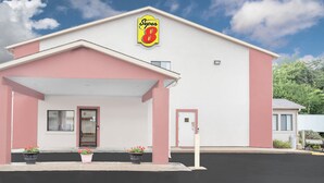 A Super 8 hotel with a white facade, pink accents, and a clear blue sky. - Super 8 by Wyndham East Moline (East Moline)