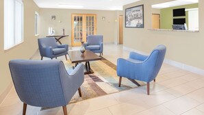 A spacious room with a large window, a wooden door, and a reception desk. - Super 8 by Wyndham East Moline (East Moline)