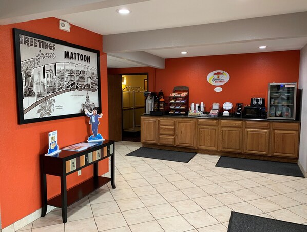 A reception area with a framed welcome sign, a coffee station, and a refrigerator. - Super 8 by Wyndham Mattoon (Mattoon)