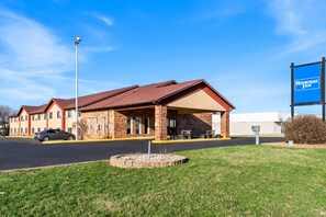 A Rodeway Inn with a brick facade, a covered parking area, and a clear blue sky.