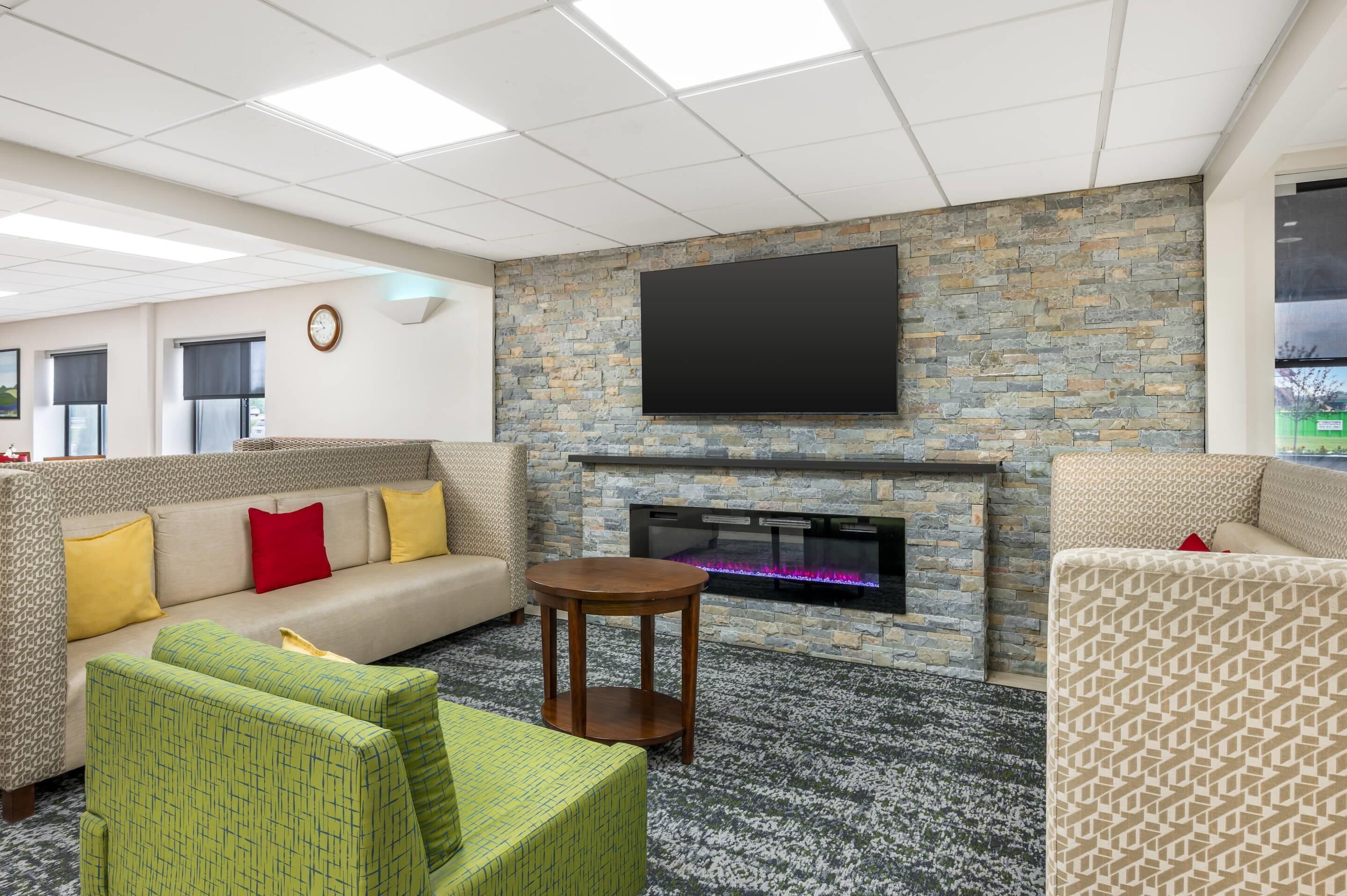 A modern lounge area with a stone wall, a flat-screen TV, a fireplace, and comfortable seating.
