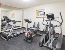 Un gimnasio con cintas de correr, elípticas y una bicicleta estática.