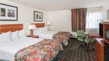 A hotel room with two beds, a television, a desk, and a chair.