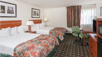 A hotel room with two beds, a television, a desk, and a chair.