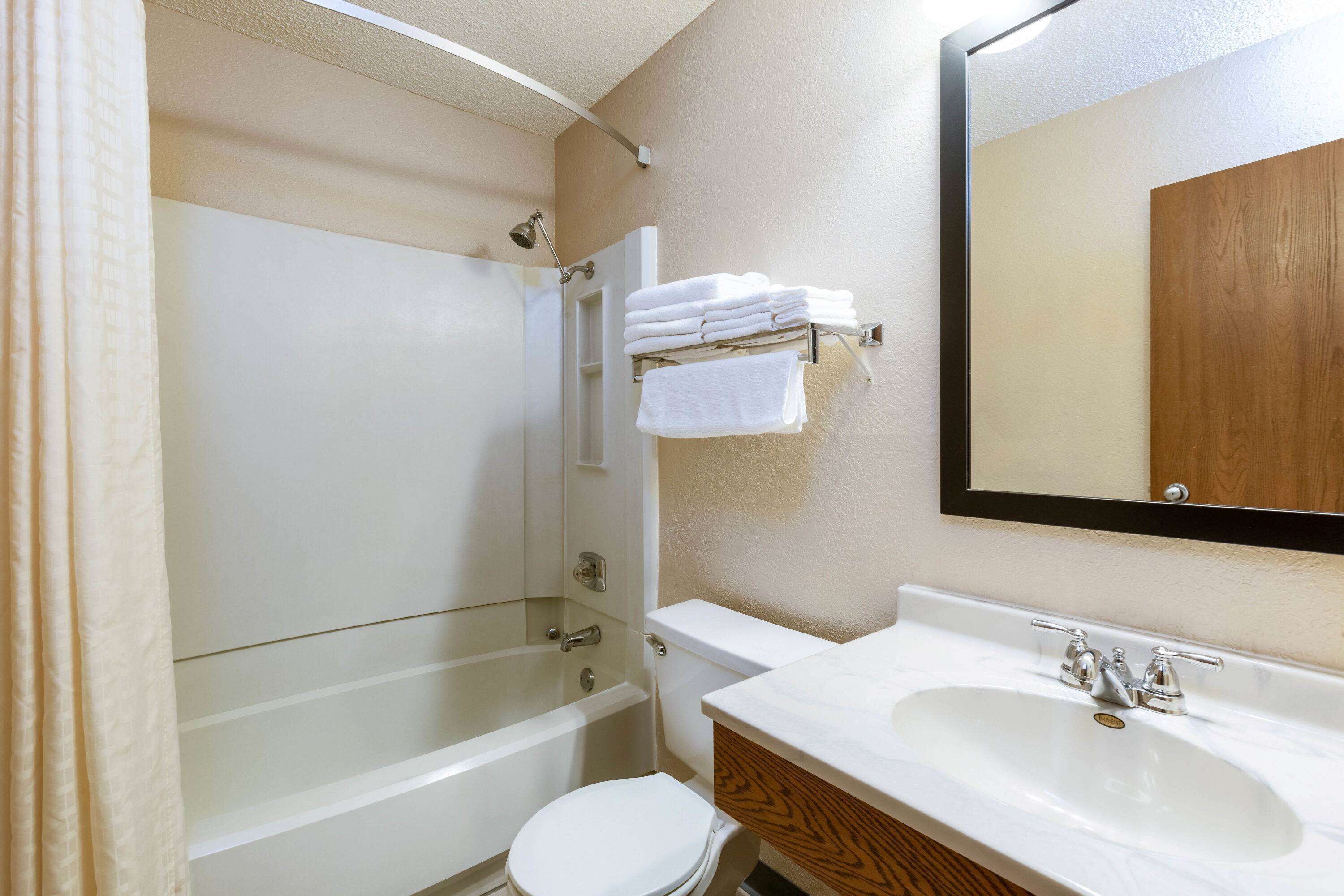 A bathroom with a bathtub, toilet, sink, and a mirror.