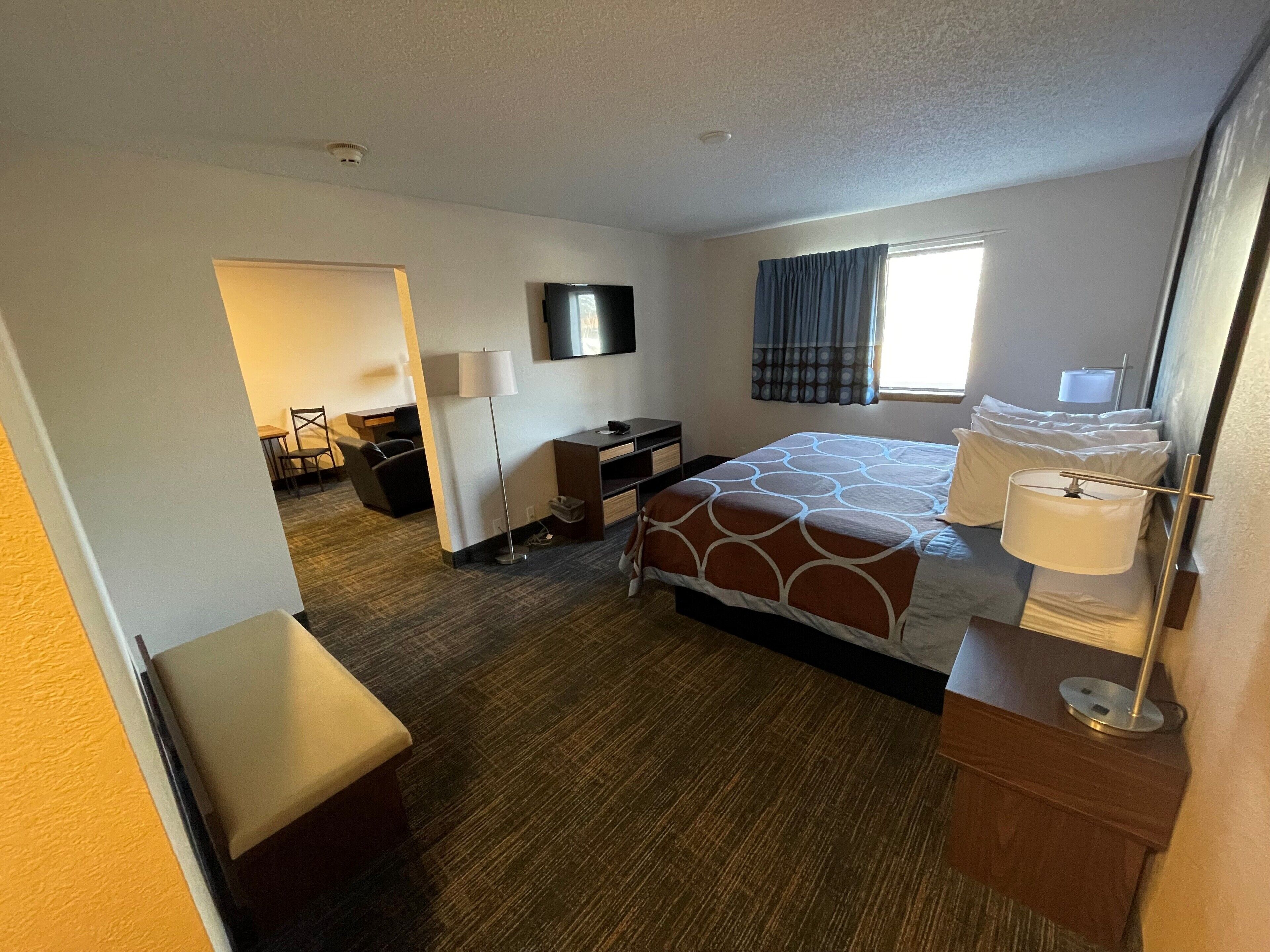 A hotel room with a bed, desk, chair, and a TV.