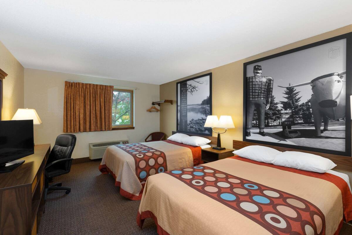 Une chambre d’hôtel avec deux lits, un bureau, une télévision et une grande affiche au mur.