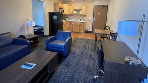 Una habitación de hotel moderna con sala de estar, kitchenette y comedor.