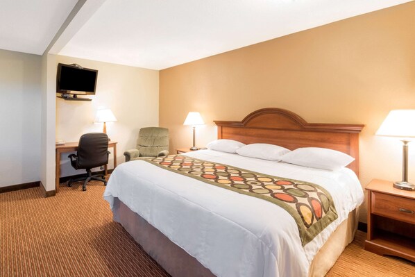 A hotel room with a bed, a desk, a chair, a TV, and two lamps.